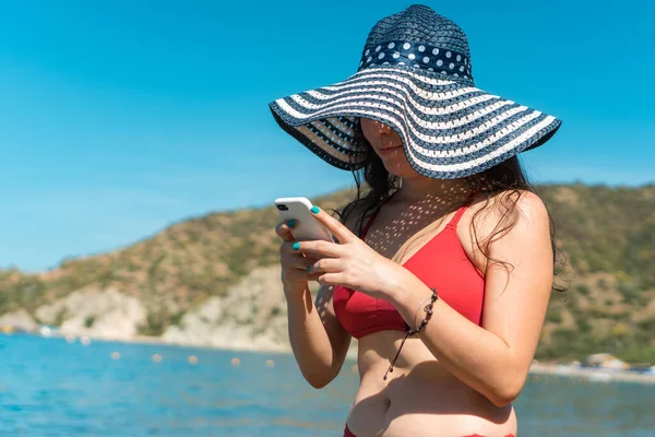 Girl on summer vacation on the beach typing a message with smartphone.
