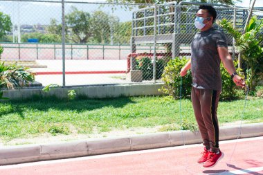 Sokaklarda ip atlayan yakışıklı genç bir sporcunun resmi..