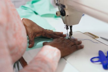 İş yerinde dikiş diken kadın elleri var. Kumaş üretimi için tekstil dikmek..