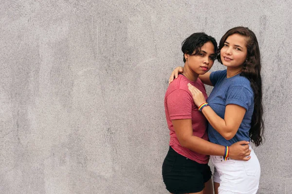 Genç lezbiyen çift, birlikte bir günün tadını çıkarırken bir caddede kucaklaşıyorlar..