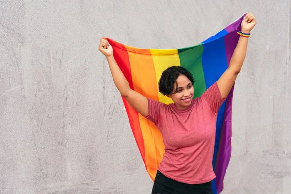 Onurlu bir bayrak taşıyan Latin bir kadın. LGTB.