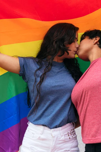 两个女孩在户外亲吻着一面带着同性恋骄傲旗的国旗 — 图库照片