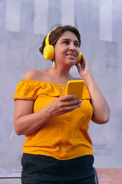Sonriente Mujer Latina Madura Usando Teléfono Celular Mientras Escucha Música —  Fotos de Stock