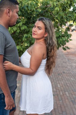 Neşeli, çoklu etnik çeşitlilikte bir çift parkta birlikte vakit geçiriyor.