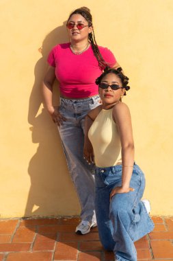 Şehir modasını gösteren sarı bir duvara poz veren çeşitli genç bayan arkadaşlar.