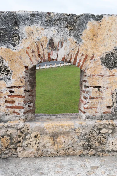 View through an arched window opening in a weathered wall at castillo san felipe del morro, a historic fortress in old san juan, puerto rico