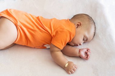 Bebek karnında dinleniyor, altın bir bilezik takıyor, barışı ve masumiyeti simgeliyor.