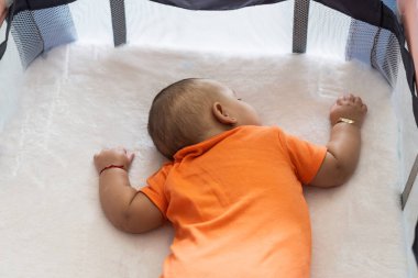 Bebek mışıl mışıl uyuyor, portatif oyun parkında dinleniyor.