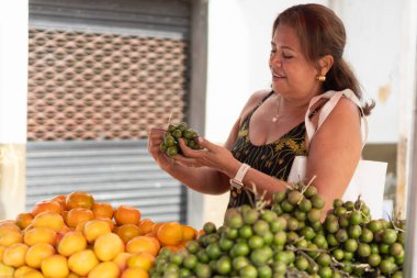Canlı bir yerel markette taze meyve seçen bir kadın.