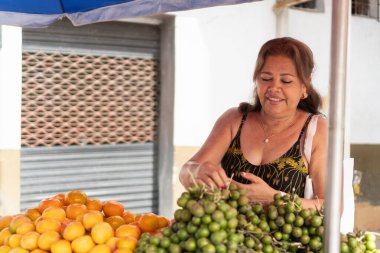 Sokakta meyve standında portakal ve mamoncillo satan bir kadın.