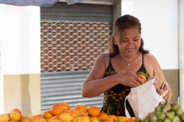 Kadın açık hava pazarından taze meyve almak için tekrar kullanılabilir bir çanta kullanıyor.