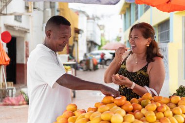 Bir kadına taze meyve satan bir adam mango tatmak için markete gidiyor.