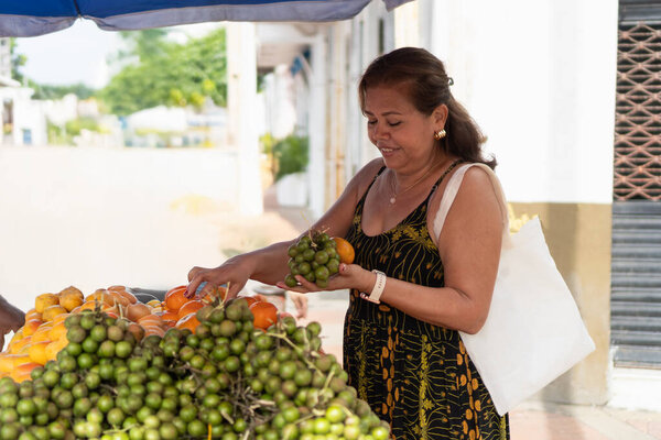 Woman smiling, choosing fruits at an outdoor street market