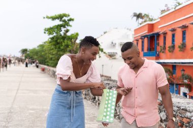 Mutlu çift tarihi bir sokakta yürürken hediye çantası açıyor.