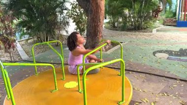 Mutlu küçük kız gün boyunca renkli bir atlıkarıncada dönerken eğleniyor.