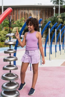 Mutlu kız oyun sahasında açık havada perküsyon enstrümanında oynarken eğleniyor.