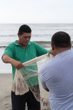 Balıkçılar okyanus kıyısında bir balık ağıyla çalışıyorlar.