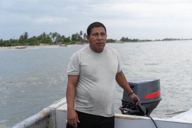 Tropikal bir sahil şeridi boyunca motorlu bir adam geziniyor.