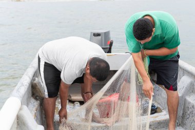 Bir teknede balıkçılar denize açılmadan önce bir balık ağı hazırlıyorlar.
