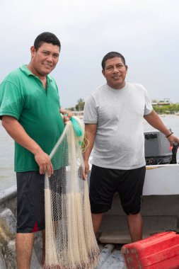 İki İspanyol balıkçı bir teknede balık ağı tutuyor ve gülümsüyor.