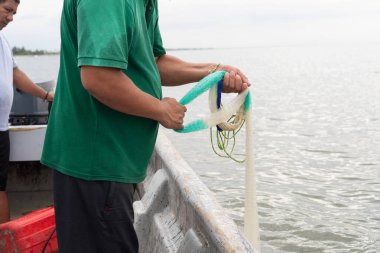 Adam sakin sudaki küçük bir tekneden balık tutmak için bir ağ hazırlıyor.