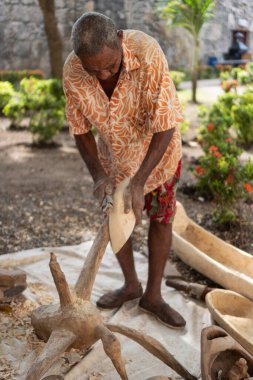 Sanatçı bir tahta parçasını şekillendirmek için el aletini kullanır, geleneksel sanat eserleri yaratır.