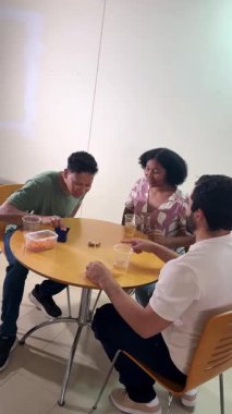 Genç çok ırklı arkadaşlar masada zar oyunu oynarken birlikte gülüp eğleniyorlar.