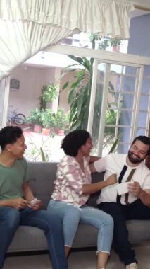 Oturma odasındaki kanepede tahmin oyunu oynarken arkadaşlarına sarılan genç bir kadın.