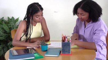 Bakıcı anne genç kızına ödevlerinde yardım ediyor, birlikte çizim yapıyor ve masa başında ders çalışıyor.