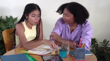 Evde bir masada ödev yaparken annesiyle atıştıracak bir şeyler paylaşan genç bir kız.