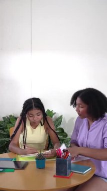 Siyah anne, genç kızına okul ödevlerinde ve masada ders çalışmasında yardım ediyor.