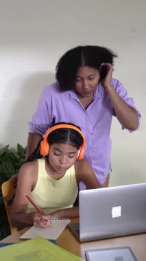 Evde dizüstü bilgisayar kullanarak genç kızına internetten öğrenmesinde yardım eden şefkatli bir anne.