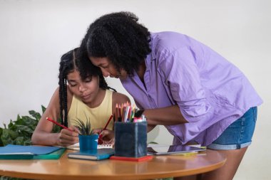Anne ya da öğretmen, genç öğrenciye ödevlerinde ve derslerinde yardım ediyor.