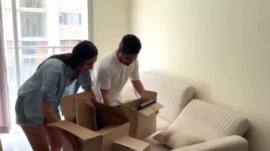 Mutlu genç çift taşınıyor ve yeni dairelerinde resim çerçeveleri olan karton kutuları açıyor.