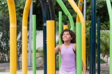 Neşeli bir oyun bahçesinde gülümseyen ve oynayan genç bir kız.