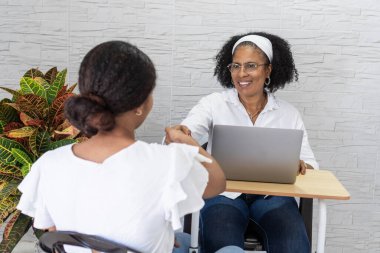 Üniversiteye kabul edilen genç bir kadın, gülümseyen akademik danışmanıyla tokalaşıyor.