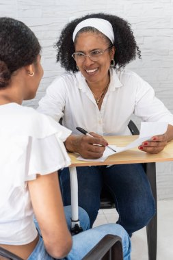 Üniversiteye kabul mektubunu genç bir öğrenciyle tartışan kadın danışman.