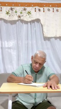 Kanepede oturan kıdemli adam düşüncelerini, anılarını ya da günlük rutinini bir deftere yazıyor.