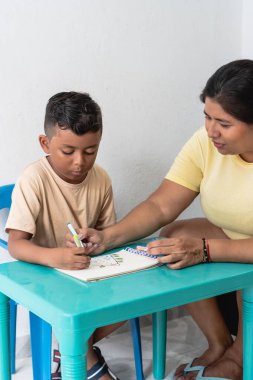Anne oğluna bir çizim ve öğrenme aktivitesinde rehberlik ediyor.