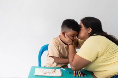 Anne, çocuğu öpüyor, resim çizerken ve öğrenirken teselli veriyor.