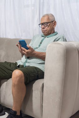 Üst düzey adam evde dinleniyor, dijital iletişim için cep telefonu kullanıyor.