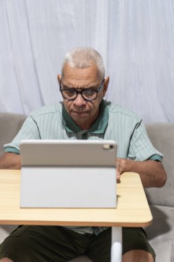 Usta adam evde dijital tablet kullanarak öğreniyor ve iletişim kuruyor.