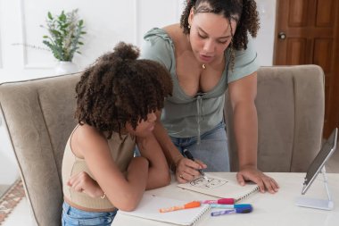 Yetişkin bir kadın çizimde genç bir kıza rehberlik ediyor, masada bilgi aktarıyor.