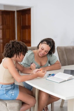 İki farklı kadın bir masada oturuyor, öğreniyor ve bilgi aktarıyor.