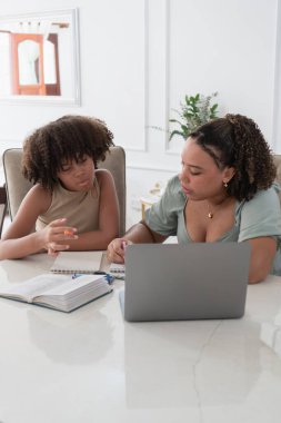 Kitaplar ve dizüstü bilgisayarla bir masada birlikte öğreniyorlar.