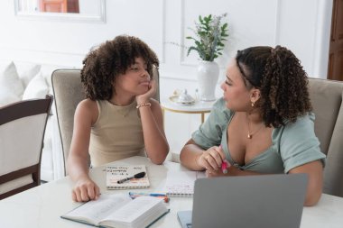 Kadın ve kız birlikte okuyor, evde tartışıyor ve öğreniyorlar.