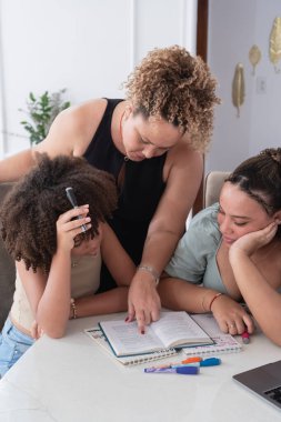 Anne, kızlarına dersleri, eğitimi ve evde öğrenimi destekliyor.