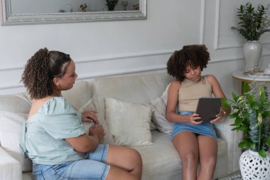 Anne ve kızı dijital tablet kullanarak bilgi aktarıyorlar.