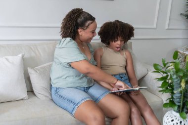 İki insan bir koltukta oturup kitap okuyor ve öğrenme anını paylaşıyor.