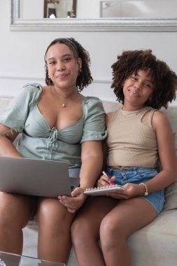 İki kız bir kanepede oturup bilgi paylaşıp öğreniyor.